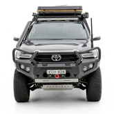 Front view of a Toyota Hilux vehicle with bull bar front bumper, roof rack and additional lights on a white background