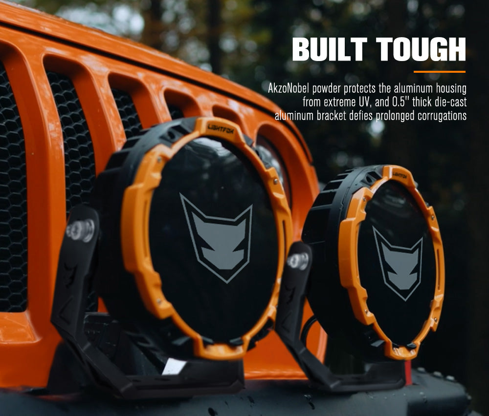 Two orange and black light covers on a vehicle grille with text about AkzoNobel powder protection. Two orange and black light covers on a vehicle grille with text about AkzoNobel powder protection.