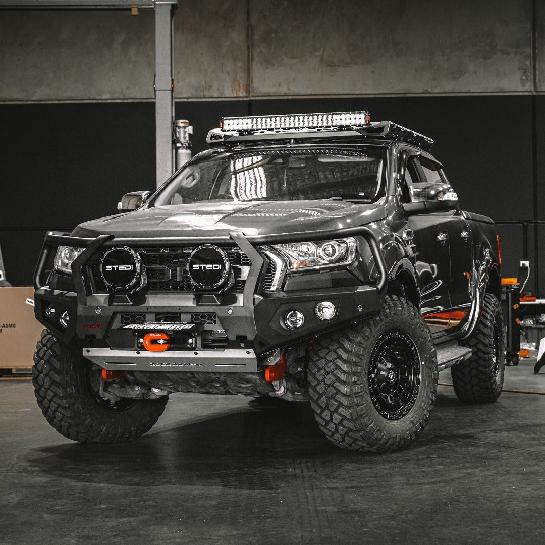 Black off-road vehicle with additional lights, Rockarmor bull bar and other modifications in a garage setting
