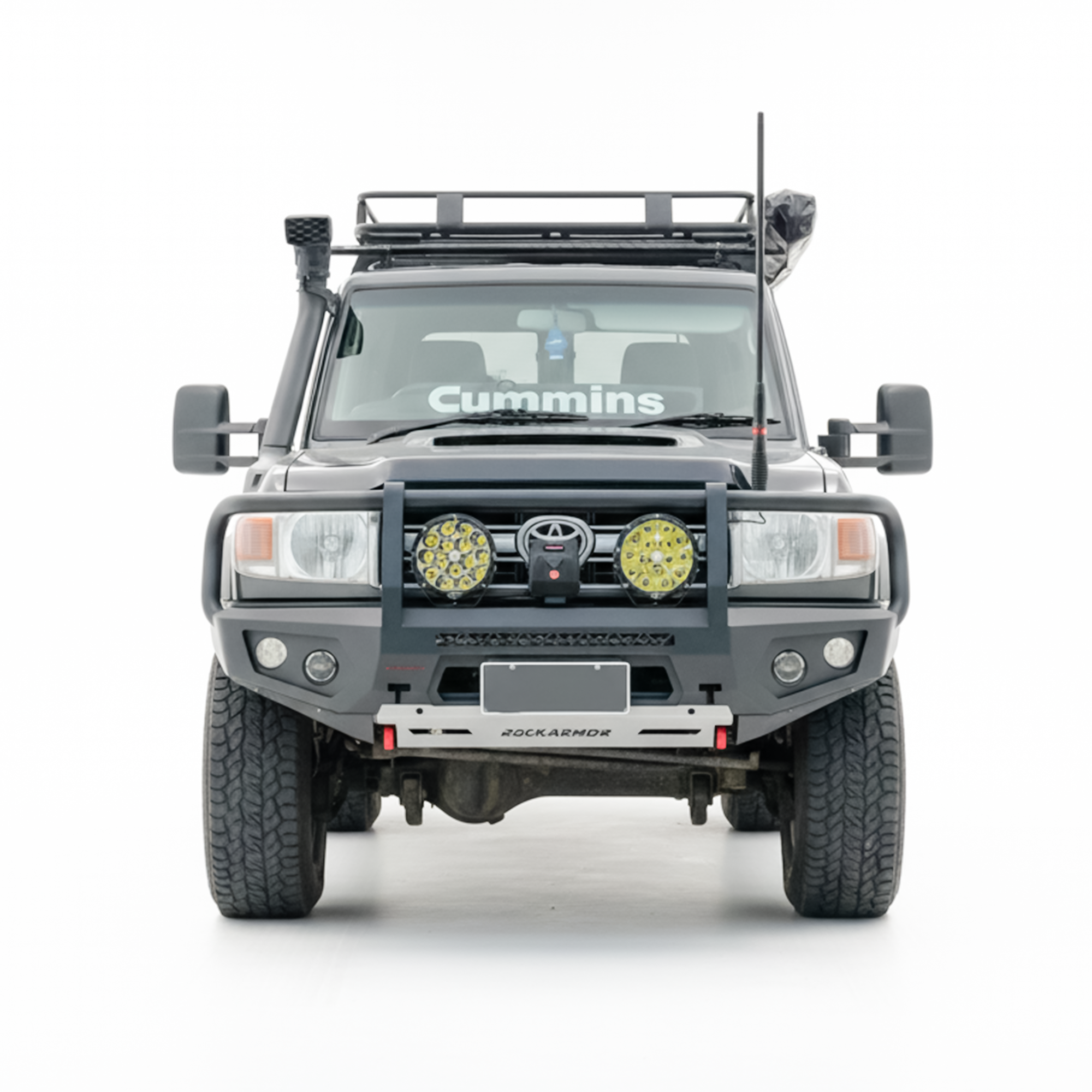 A front-facing view of a black off-road Toyota Land Cruiser with a heavy-duty front bumper, dual round auxiliary lights, a roof rack, isolated on a white background.