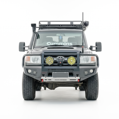 A front-facing view of a black off-road Toyota Land Cruiser with a heavy-duty front bumper, dual round auxiliary lights, a roof rack, isolated on a white background.