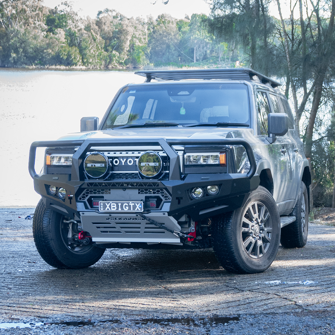 Toyota SUV with a large front bumper and bull bar parked on a road near a body of water.