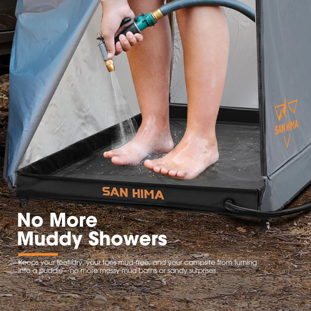 Person standing on a shower tent base, using a camping shower system with 'SAN HIMA' branding outdoors.