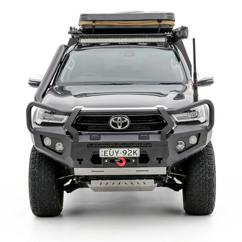 Front view of a Toyota Hilux vehicle with bull bar front bumper, roof rack and additional lights on a white background