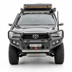 Front view of a Toyota Hilux vehicle with bull bar front bumper, roof rack and additional lights on a white background