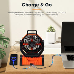 Portable fan with built-in battery and dual USB ports on a desk with laptop and phone.