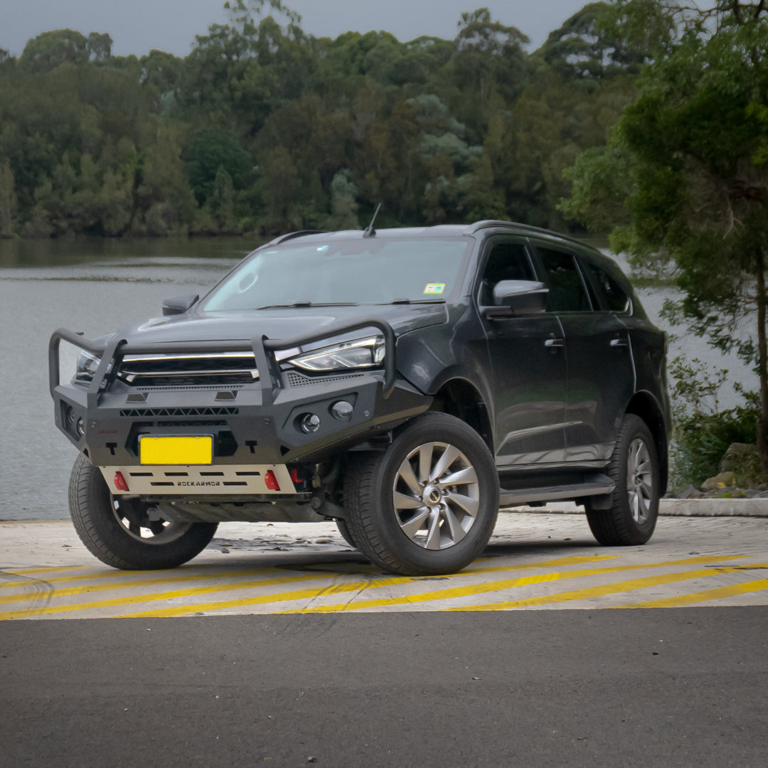 Black Isuzu SUV with a front bumper bull baron a road with trees in the background