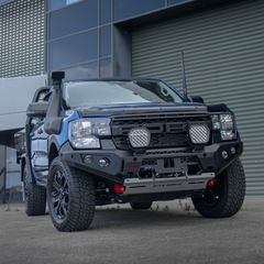 Blue Ford Ranger bakkie pickup truck with off-road modifications and Rockarmor bumper bull bar in front of a building