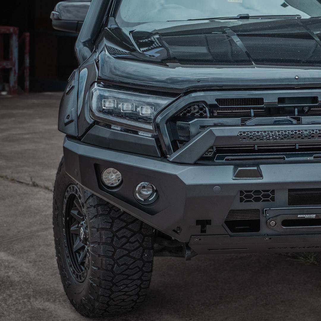 Close-up of a truck's front bumper and grille in an industrial setting