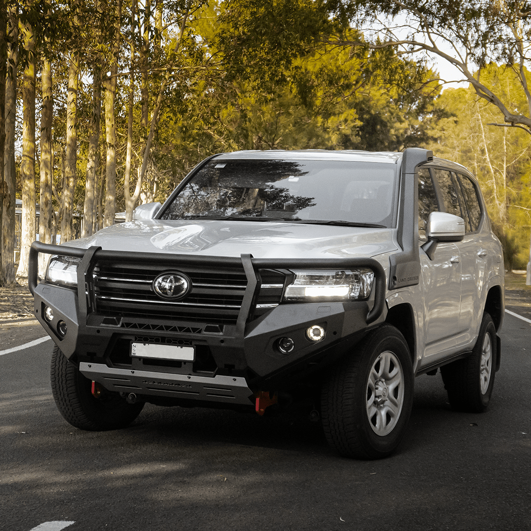 Gray Toyota SUV with black Rockarmor bull bar on a road with trees in the background