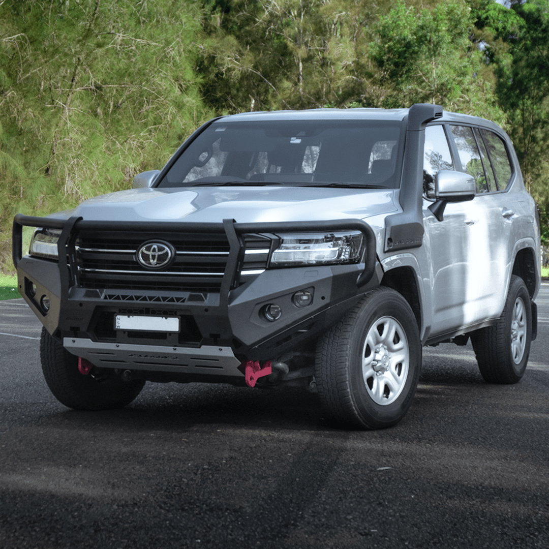Silver Toyota SUV with black bullbar on a road with trees in the background