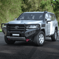 Silver Toyota SUV with black bullbar on a road with trees in the background