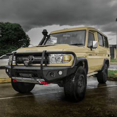 Beige Toyota Land Cruiser with black Rockarmor bull bar on a wet road with dark clouds in the background