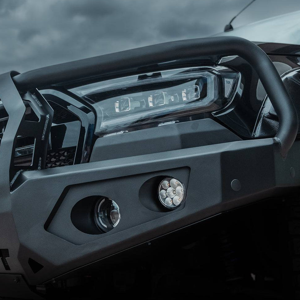 Close-up of a black off-road vehicle front bumper and bull bar with integrated LED lights, shown outdoors under a cloudy sky. The brand name ROCKARMOR is displayed at the top.