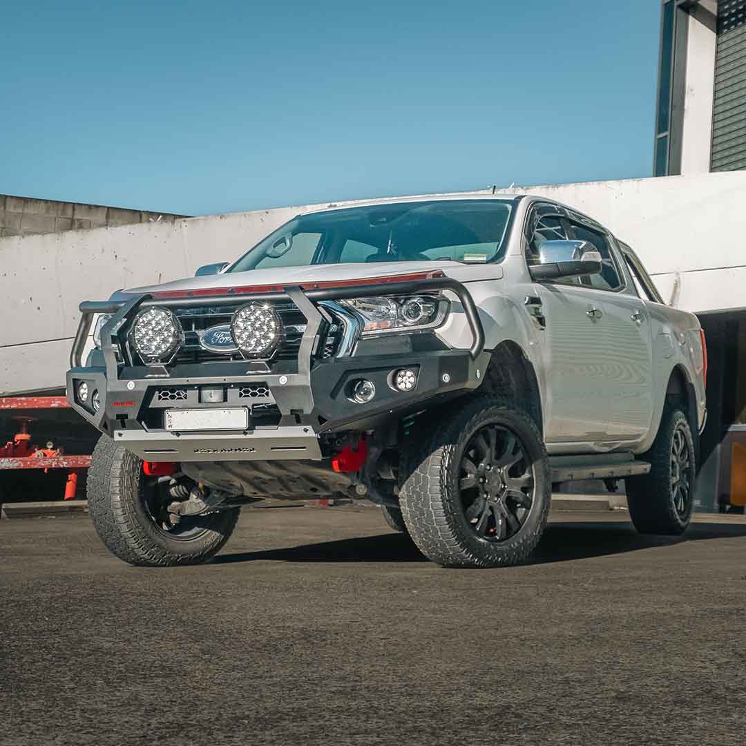 Silver Ford bakkie with additional lights and Rockarmor bull bar bumper on a concrete surface.