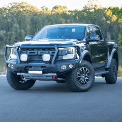 Gray Ford Ranger Raptor bakkie pickup truck with Rockarmor front bumper bull bar parked outside on a road near a body of water.