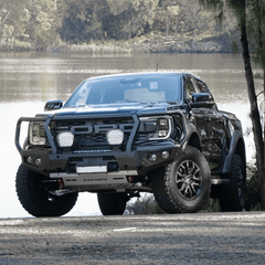 Gray Ford Ranger Raptor bakkie pickup truck with Rockarmor front bumper bull bar parked near a body of water.