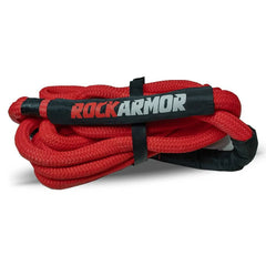 A coiled red kinetic recovery rope with black protective ends and a black wrap featuring the ROCKARMOR logo in red and white, photographed on a white background.