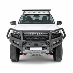 A white Toyota Hilux pickup truck bakkie shown from the front on a clean white studio background, fitted with a heavy-duty black Rockarmor front bumper guard bullbar and a roof-mounted light bar.