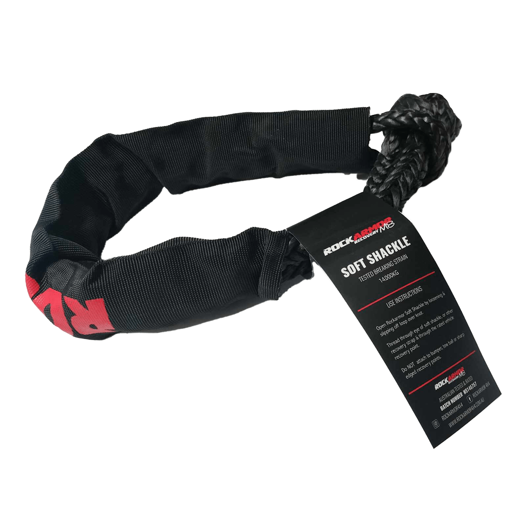 A black nylon soft shackle with a black braided rope end and a black hangtag, photographed on a clean white background. The tag shows the brand ROCKARMOR and the text SOFT SHACKLE.