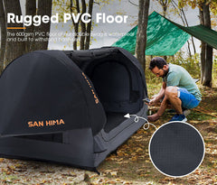 Black tent with 'San Hima' branding on a rugged PVC floor, surrounded by trees and grass.