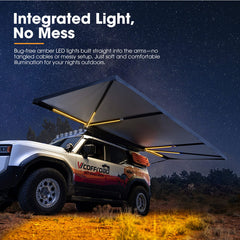 Off-road vehicle with an extended roof tent awning illuminated by amber LED lights against a night sky.