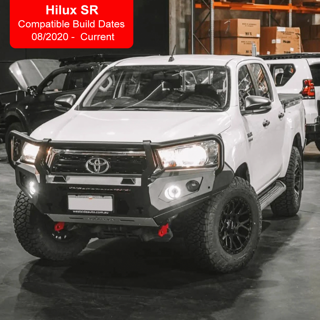 A white Toyota Hilux SR pickup truck shown from the front three-quarter angle in a warehouse setting, fitted with a black Rockarmor front bull bar, black front grille, black fog lights, and black off-road wheels. A red text overlay in the top left reads 'Hilux SR Compatible Build Dates 08/2020 - Current'.