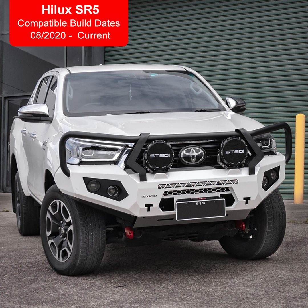 A white Toyota Hilux SR5 bakkie pickup truck shown from the front three-quarter angle, fitted with a Rockarmor black steel front bumper guard and round front grille lights. The image includes a red text overlay in the top-left corner stating 'Hilux SR5 Compatible Build Dates 08/2020 - Current'.
